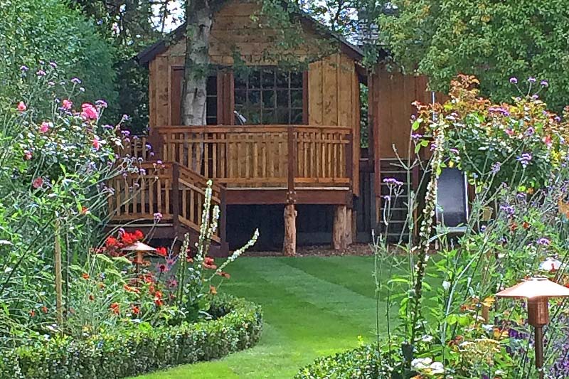 Bespoke woodland cabin design treehouse, with games room and play tower, nestled in surrounding trees